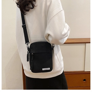 Back view of model wearing a compact black canvas crossbody bag with adjustable strap