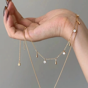 Detail of Italian brushed Vatican cross and golden teardrop pendant on multi-layer necklace