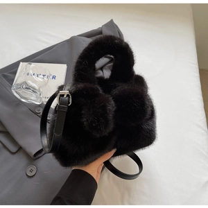 Detail der schwarzen Plüsch-Beuteltasche mit Pelzstruktur und Leder-Schultergurt