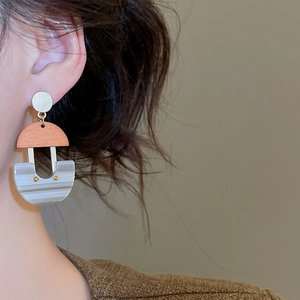 Close-up of geometric U-shaped resin earrings with marble pattern and gold metallic studs