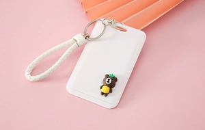 Close-up of white cartoon card holder with braided wrist strap and bear charm