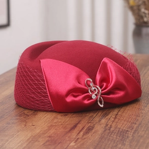 Detail of red wool pillbox hat with mesh veil and rhinestone treble clef brooch