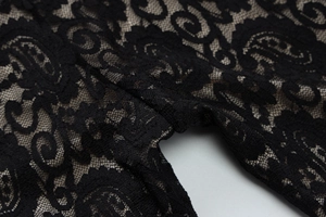 Detailed close-up of intricate black lace floral patterns and stitching on a halter jumpsuit