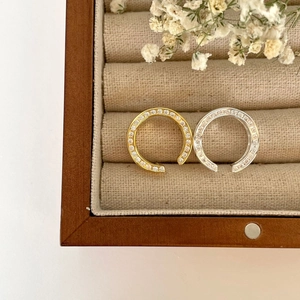 Close-up of gold and silver horseshoe rings with cubic zirconia on linen tray