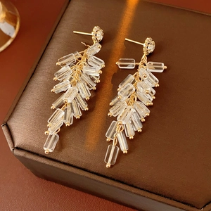 Detailed view of gold firecracker earrings with crystals and transparent tassels