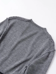 Detail of grey knitted wool jacket showing frayed edge design and back collar texture