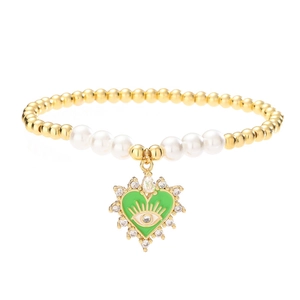 Beaded heart evil eye bracelet with gold beads and white pearls on white background