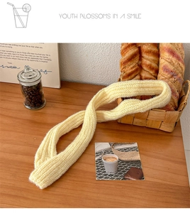 Detailed view of yellow waffle-knit skinny scarf on wooden table with warm aesthetic props