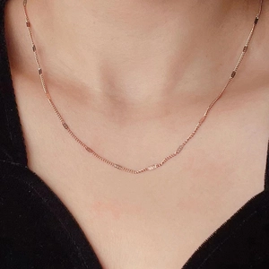 Detail of rose gold titanium necklace with sequins worn by a model on the neck