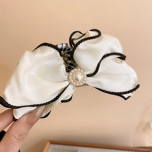 Detailed view of the large silk bow hair claw clip with pearl embellishment and black edging
