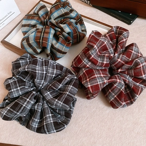 Detailed view of three vintage plaid scrunchies with elegant ruffled fabric textures