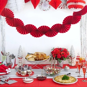 Close-up of red paper fan garland hanging above a festive party table setting