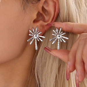 Modern silver sunburst stud earrings in stainless steel on a female model