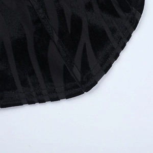 Macro shot of black flocked velvet fabric texture and double stitching detail on the hemline