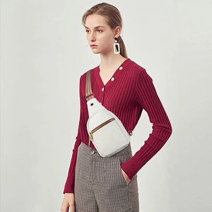 Close-up of white bohemian canvas crossbody bag with patterned strap on model