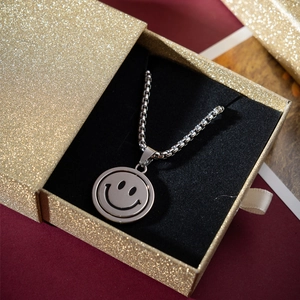Silver smiley face pendant necklace displayed in a gold glitter jewelry gift box