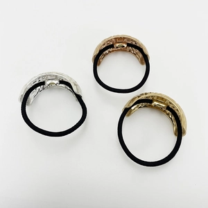 Detail of three elastic hair ties with textured alloy rings in silver, rose gold, and gold