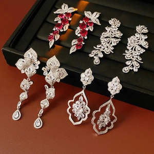 Vue détaillée de boucles d'oreilles pompons en zircon argenté avec cristaux rouges sur velours