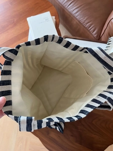 Détail d'un sac cabas en toile rayée montrant la poche intérieure et la doublure spacieuse crème