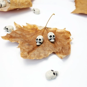 Detailed view of mini white skull beads on a dried autumn leaf for Halloween DIY