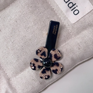 Macro shot of leopard print acetate flower clip with rhinestones and handmade engraving