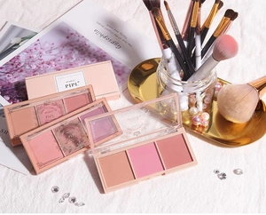 Detailed view of matte three-color blush palette with makeup brushes and elegant props