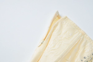 Dettaglio ravvicinato della cerniera invisibile su pizzo floreale crema con strass