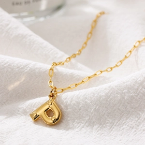 Detailed view of 3D bubble letter P pendant on a golden paperclip chain necklace