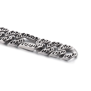 Detail view of flat Cuban link chain with dark etched patterns in stainless steel