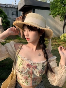 Detail of straw hat with fringe edge and ribbon paired with a floral puff sleeve top