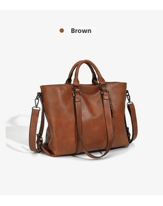 Detail view of brown leather tote bag with lychee texture and metallic buckles