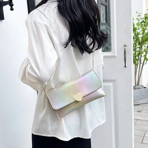 Iridescent laser heart envelope bag with gold chain strap shown on model outdoors