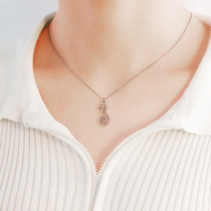 Détail d'un collier pendentif hippocampe argenté porté sur un mannequin en tricot blanc