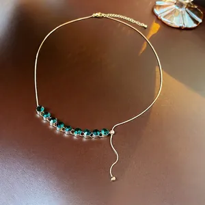 Collana girocollo placcata oro con zirconi verde smeraldo su sfondo in pelle premium