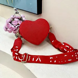 Close-up of heart-shaped red crossbody bag with patterned shoulder strap on decor
