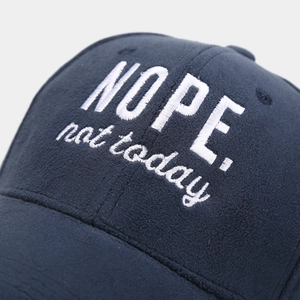 Detailed close-up of white NOPE embroidery on a dark blue thick cotton baseball cap