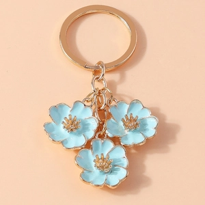 Detailed shot of golden keychain with three light blue enamel peach blossom charms