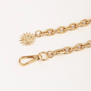 Detail of matte gold punk chain belt with ornate sun pendant and rotating lobster clasp