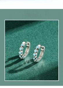 Gros plan de créoles en argent sterling S925 avec turquoise bleue sur fond texturé