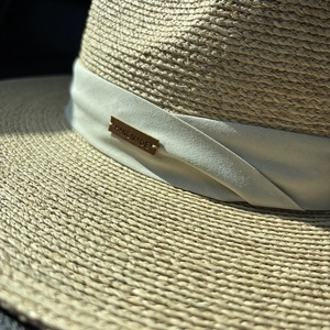Handmade raffia sun hat with woven texture and decorative ribbon with leather tag