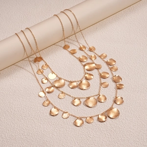 Detailed shot of triple-layer gold sweater necklace with hammered circular coin pendants