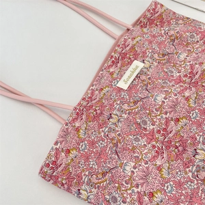 Gros plan du sac fourre-tout en toile rose avec motifs fleurs et oiseaux et texture fine