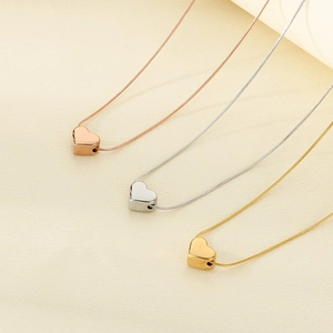 Vue détaillée de trois pendentifs cœur en or rose, argent et or sur chaînes serpent