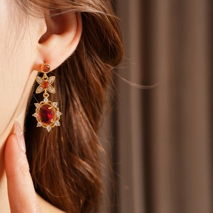 Nahaufnahme von Vintage-Goldohrringen mit ovalem rotem Edelstein und Zirkonia am Model