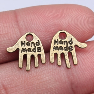 Pair of bronze palm-shaped metal charms with Hand Made engraving on fingertips