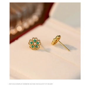 Detailed view of s925 silver flower stud earring with green gemstones and golden finish