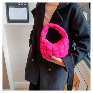 Close-up of rose pink quilted cloud bag styled with a black coat for a trendy look