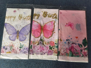 Detail view of three packaged butterfly and floral themed disposable plastic tablecloths