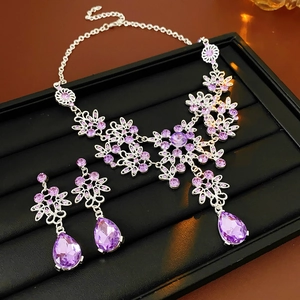 Detail view of silver vintage jewelry set with purple crystals on black velvet display