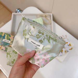 Close-up of a floral satin mini pouch with a white zipper and Simple Wish woven label